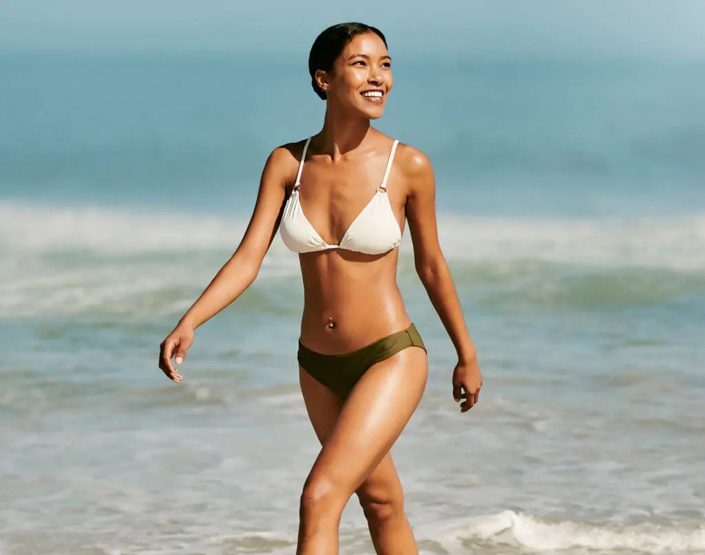 Fit, beautiful and toned bikini model on beach enjoying fun and relaxing summer holiday by ocean and sea while wearing a swimsuit. Smiling, happy and walking woman in swimwear on a tropical vacation Cellulite Treatment in West Palm Beach and Jupiter, FL