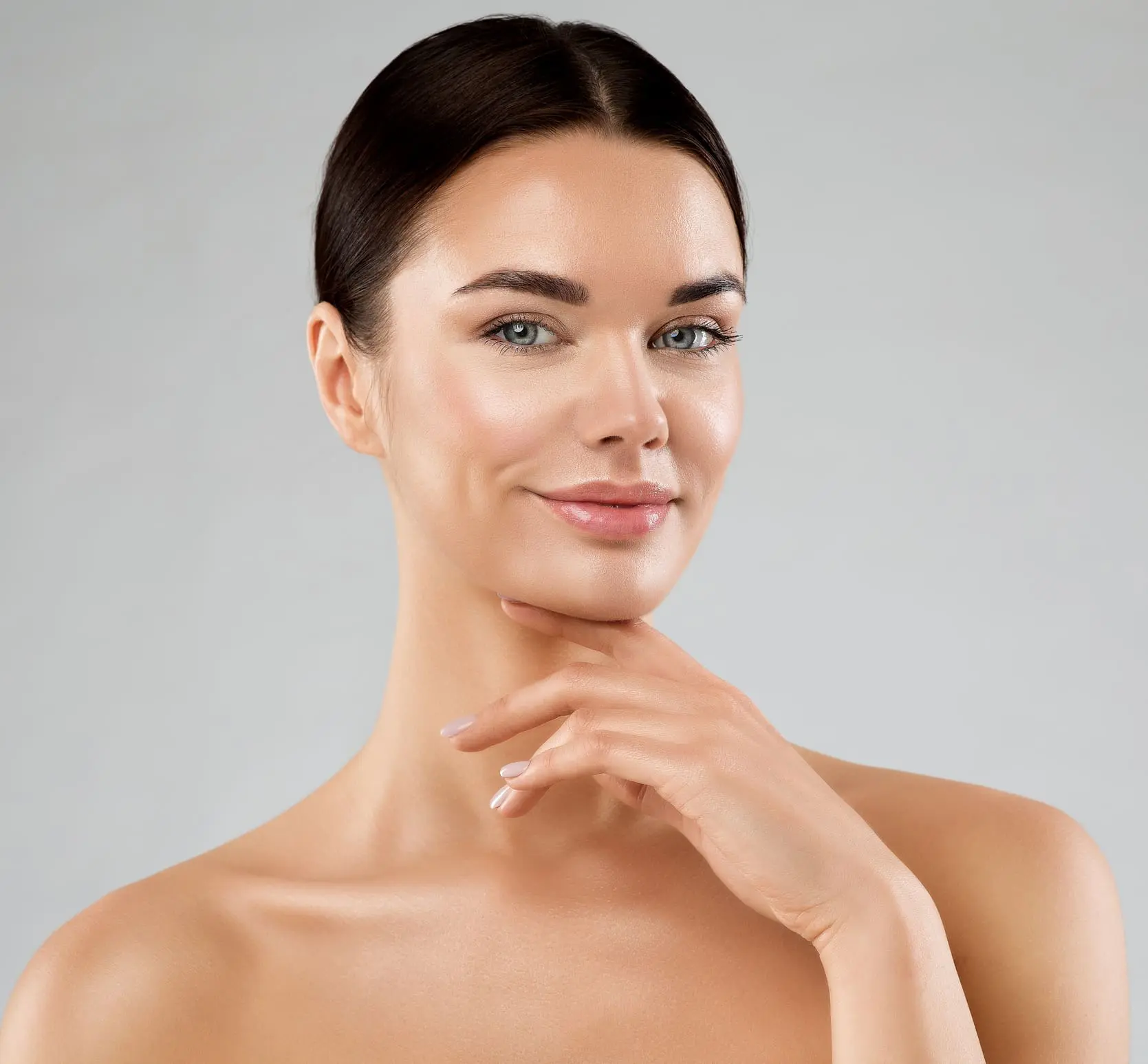 Beauty Model with Smooth Skin touching Chin. Happy Young Woman with Perfect Face Make up over White. Women Facial Spa Cosmetics and Anti Age Cosmetology. Female Plastic Surgery Chin Implants in West Palm Beach and Jupiter, FL